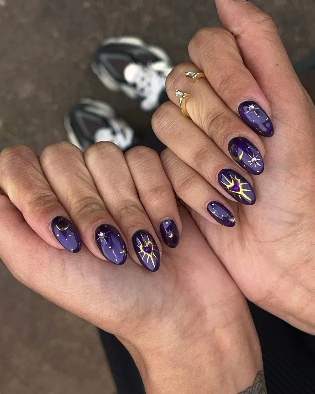 Dark purple starburst nails with gold lines and gem centers