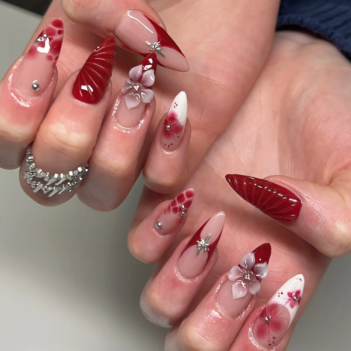 3D florals and red aura accents on long pointed nails