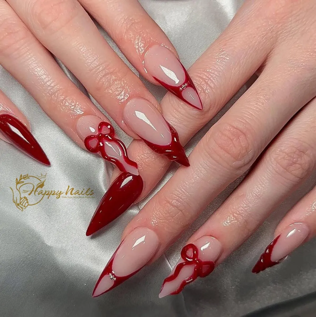 Stiletto nude-and-red French tips with raised bow accents
