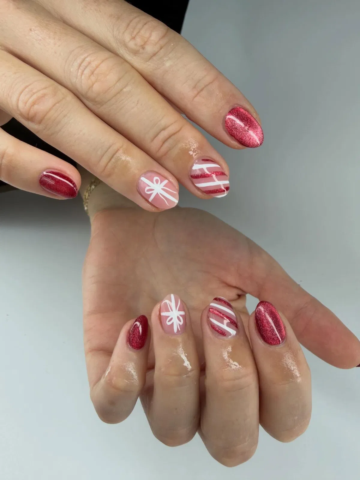 Short red shimmer nails with white bow and stripe accents