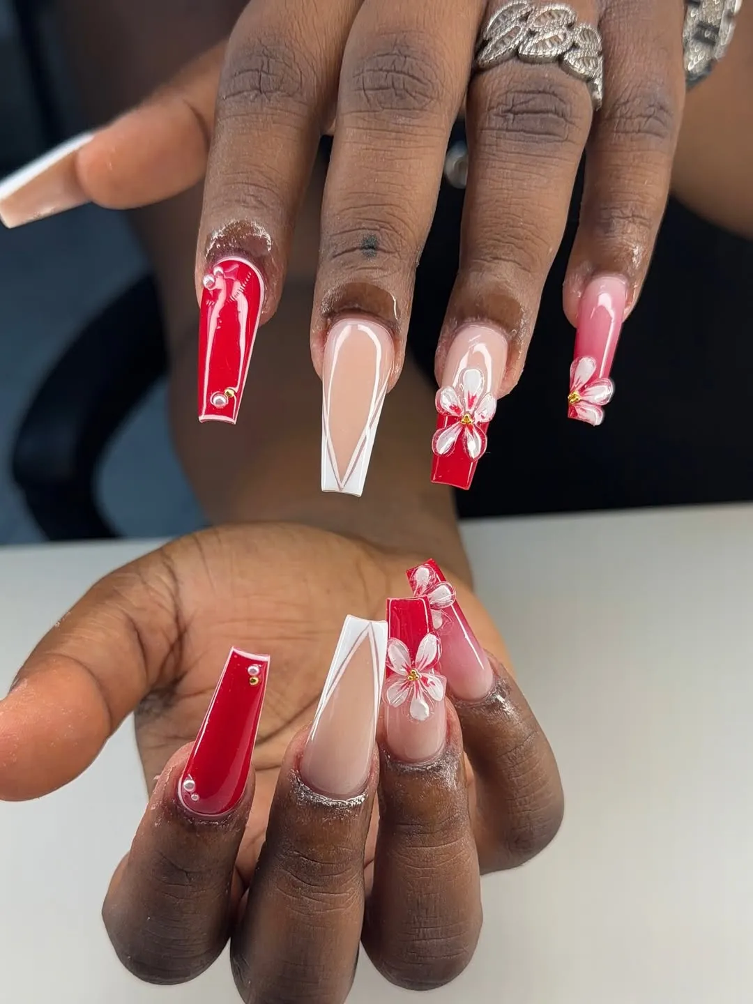 Red-and-nude coffin nails with white V lines and floral accents