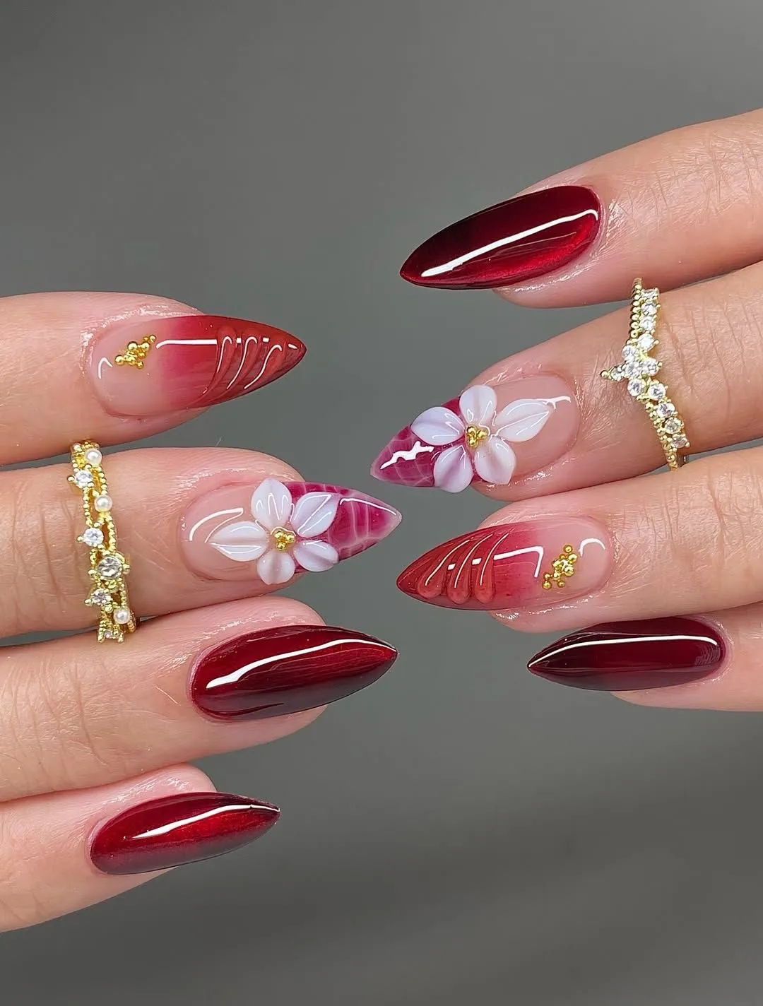 Deep red almond nails with white 3D flowers and gold beads