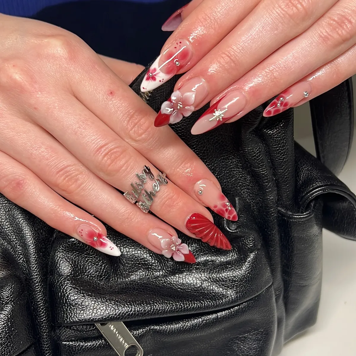 Nude-and-red stiletto nails with 3D flowers and rhinestones