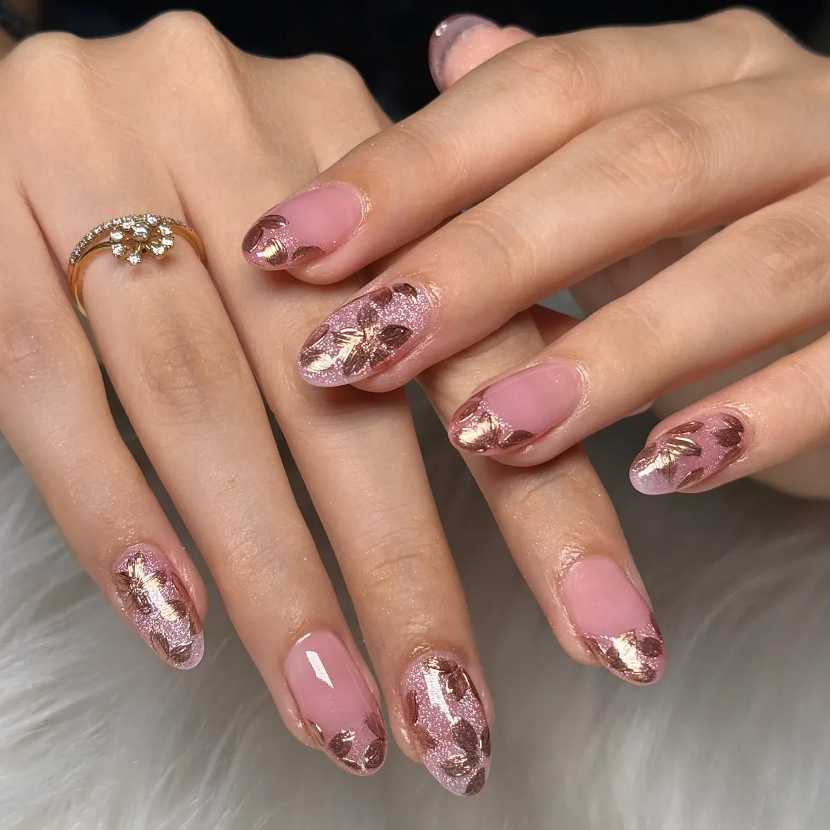 Pink nails with rose-gold glitter and metallic leaf/floral motifs