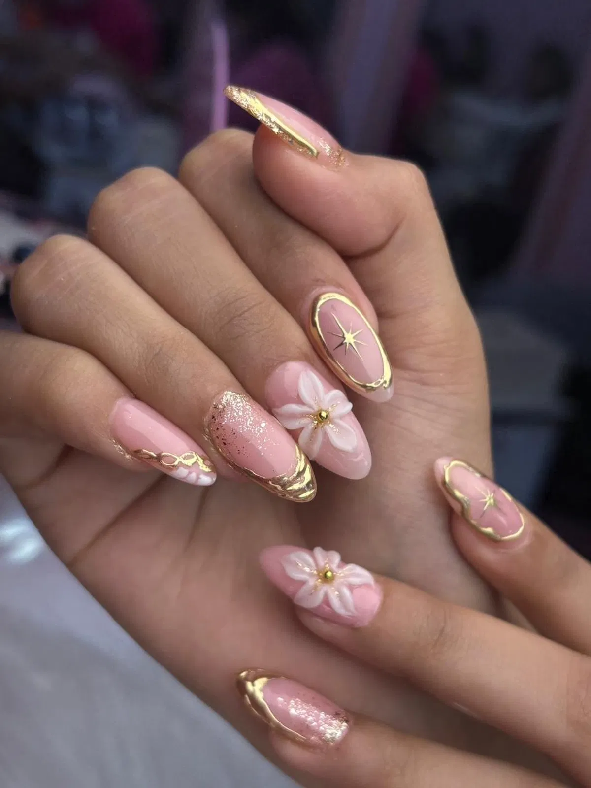 Light pink almond nails with gold outlines and 3D flowers