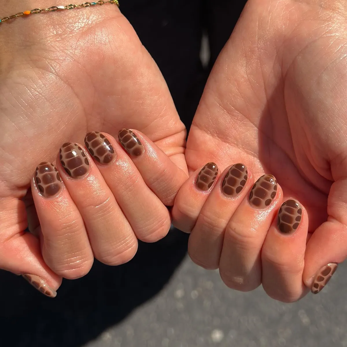 Short glossy brown nails with all-over cell pattern