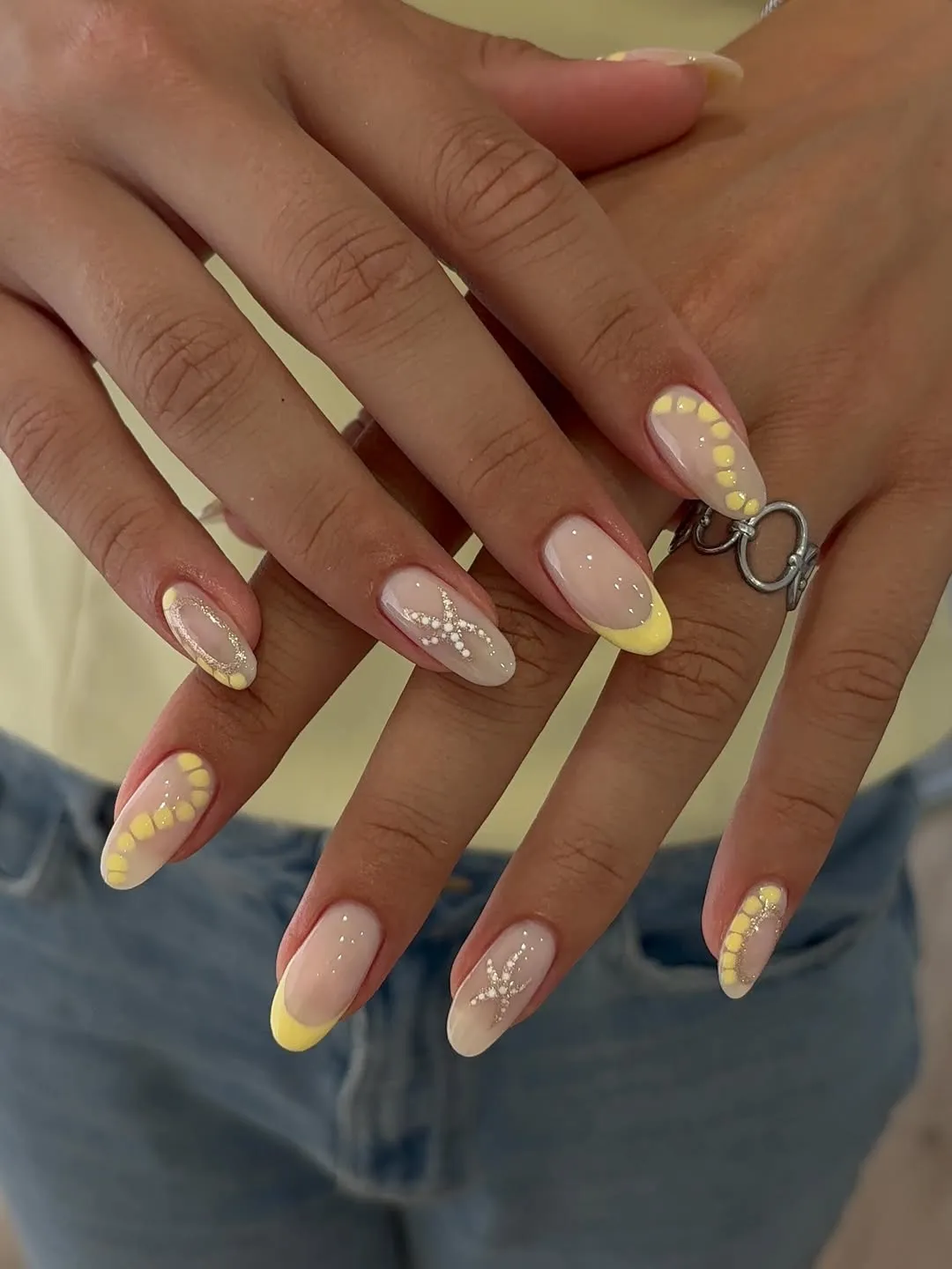 Pale yellow French tips with dotted arcs and rhinestone star accents