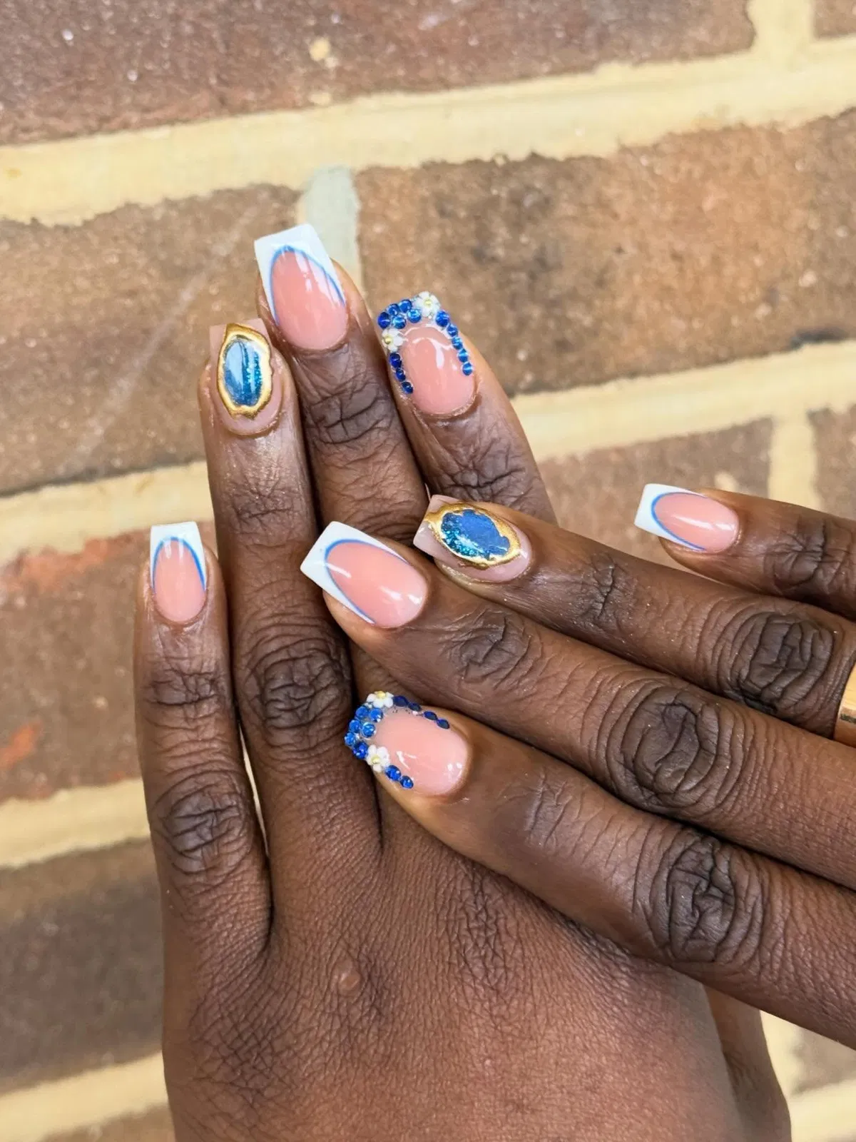 White French tips with blue outlines, blue ovals, and rhinestone clusters