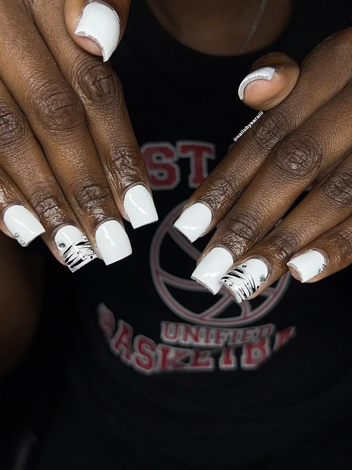 Solid white nails with black stripe accents and small rhinestones