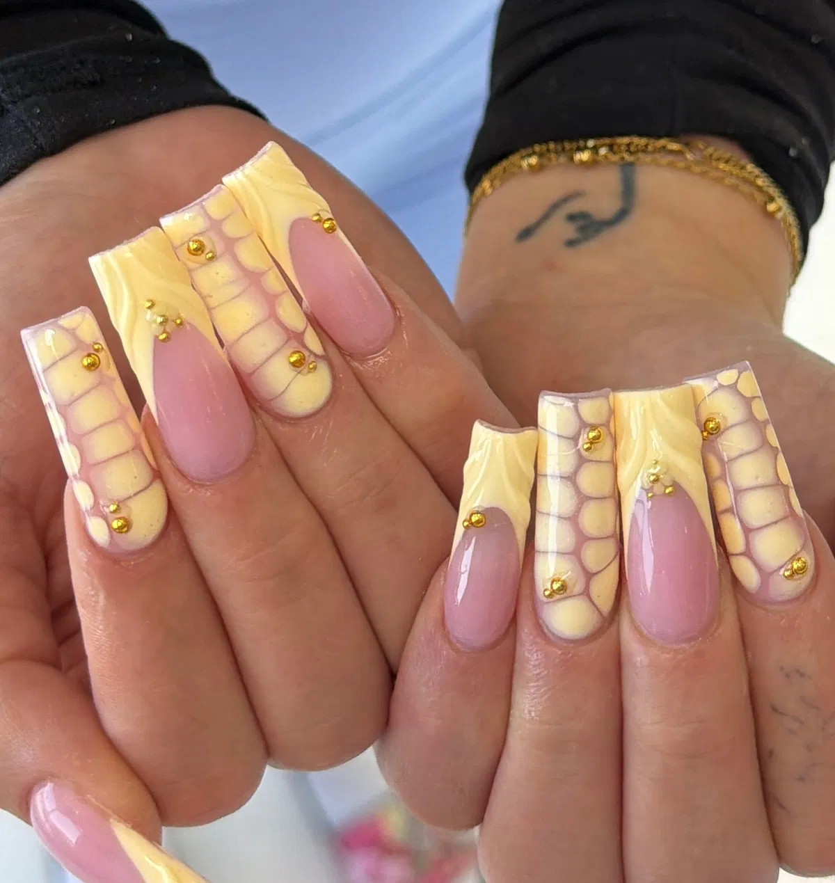 Pale yellow grid-pattern nails with gold stud accents