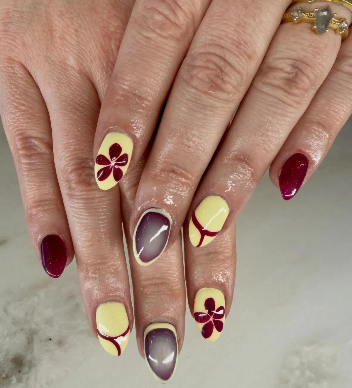 Pale yellow and burgundy floral nails with purple gradient accents