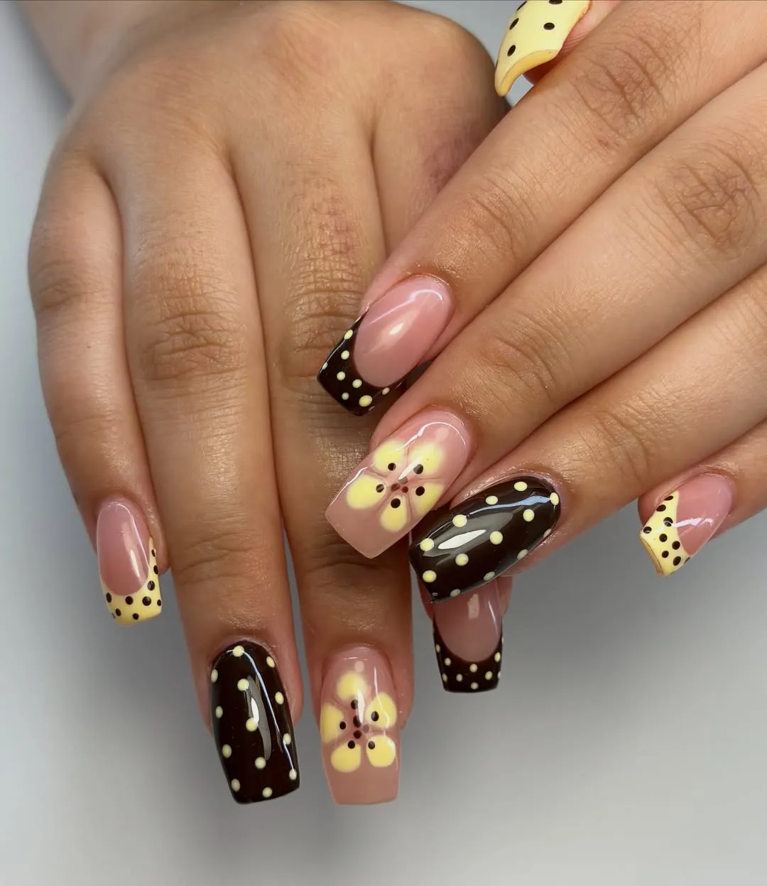 Brown-and-yellow polka dot nails with pale yellow flower accents