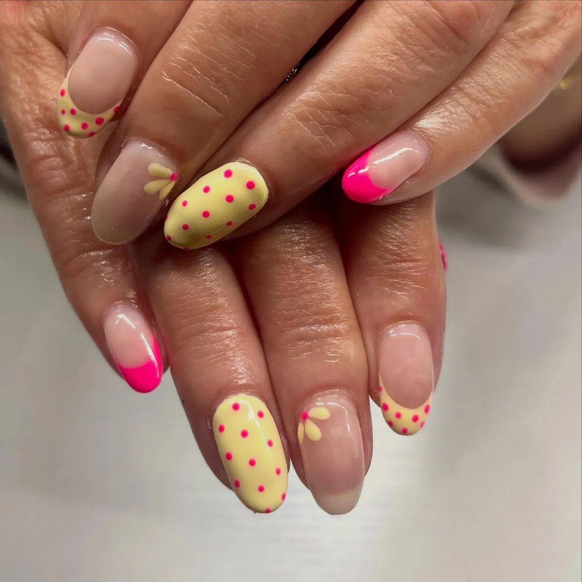 Nude base with hot-pink tips, yellow polka dots, and tiny petal accents