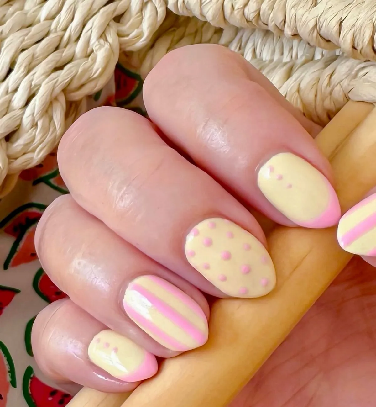 Pastel yellow nails with soft pink dots, stripes, and gradient tips