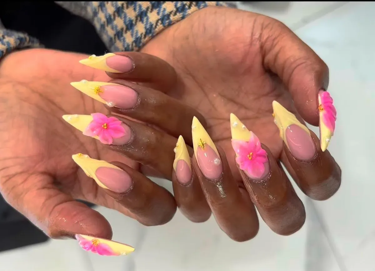 Extra-long pointed nails with angled yellow tips and 3D pink flowers