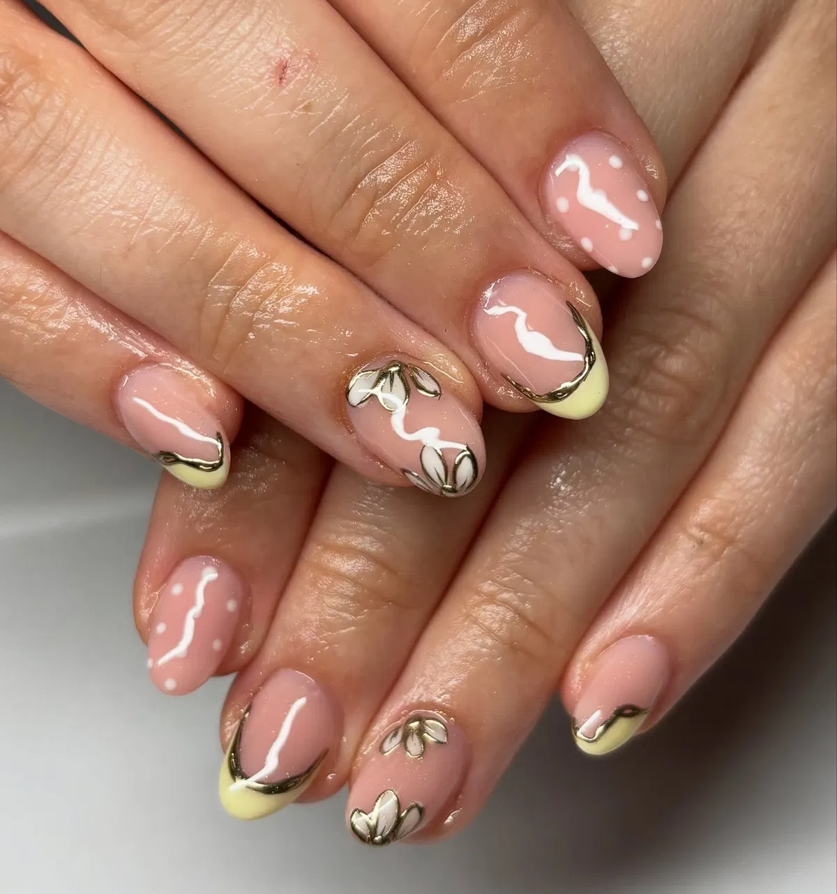 Pale yellow French tips with gold outlines and white dots