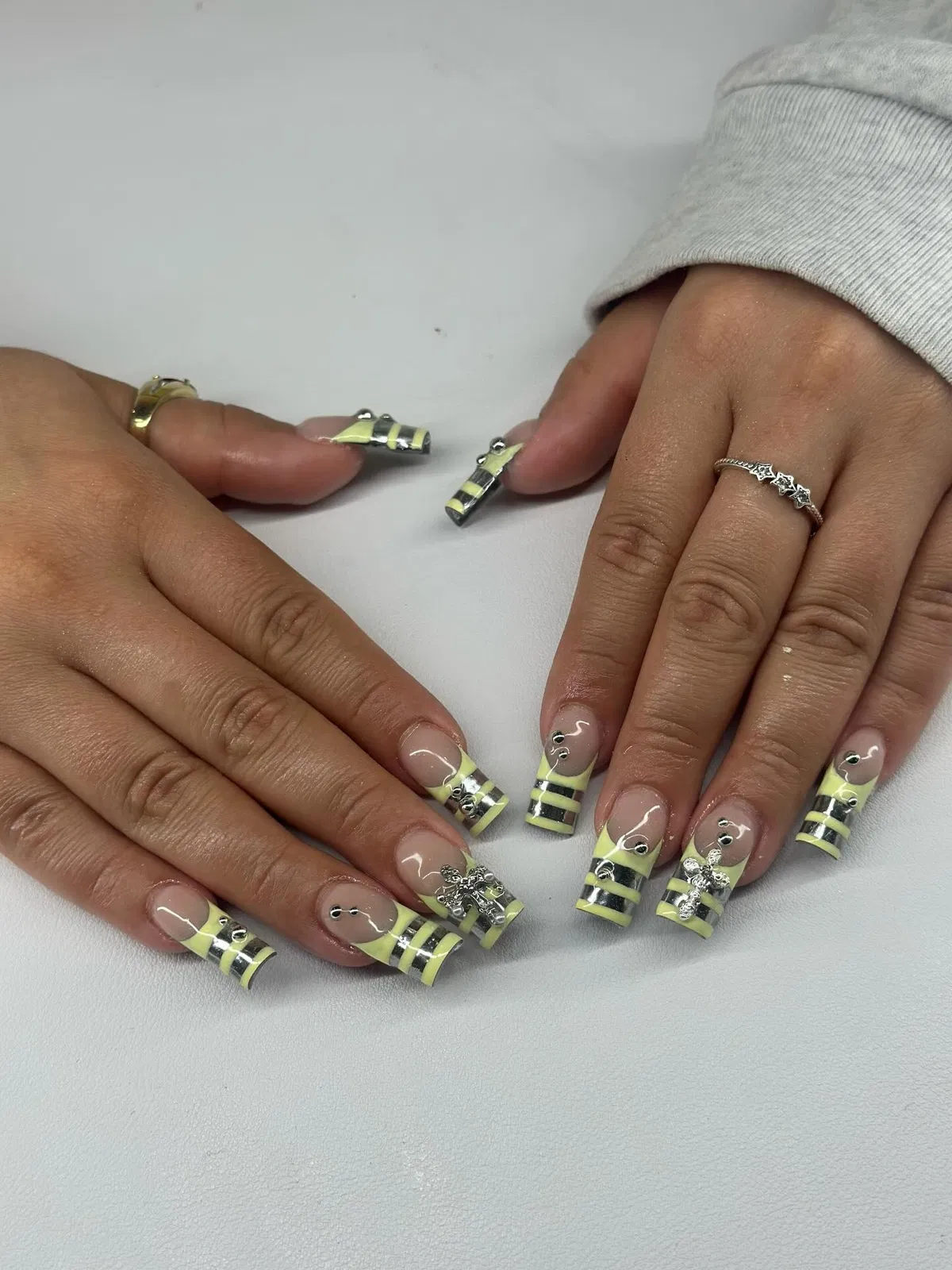 Striped neon yellow-green tips with silver bows and rhinestones