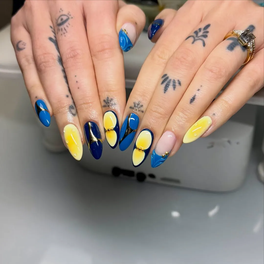 Blue and yellow graphic nails with gold bead accents