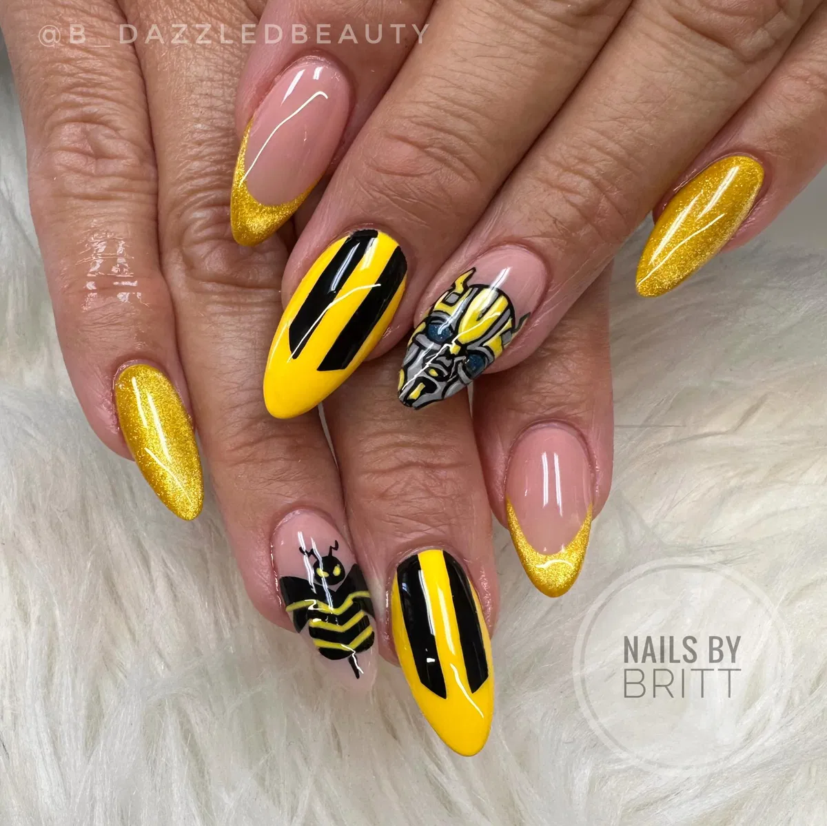 Gold glitter French tips with bold black-and-yellow graphic accents