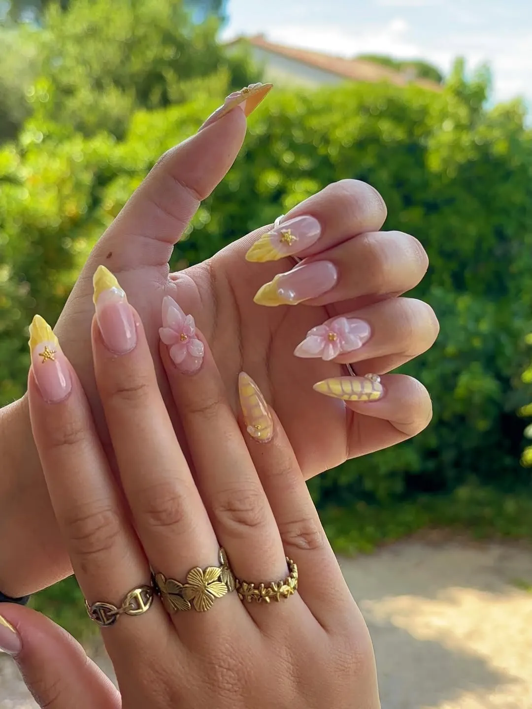 Soft yellow French tips with 3D pink flowers and gold star accents