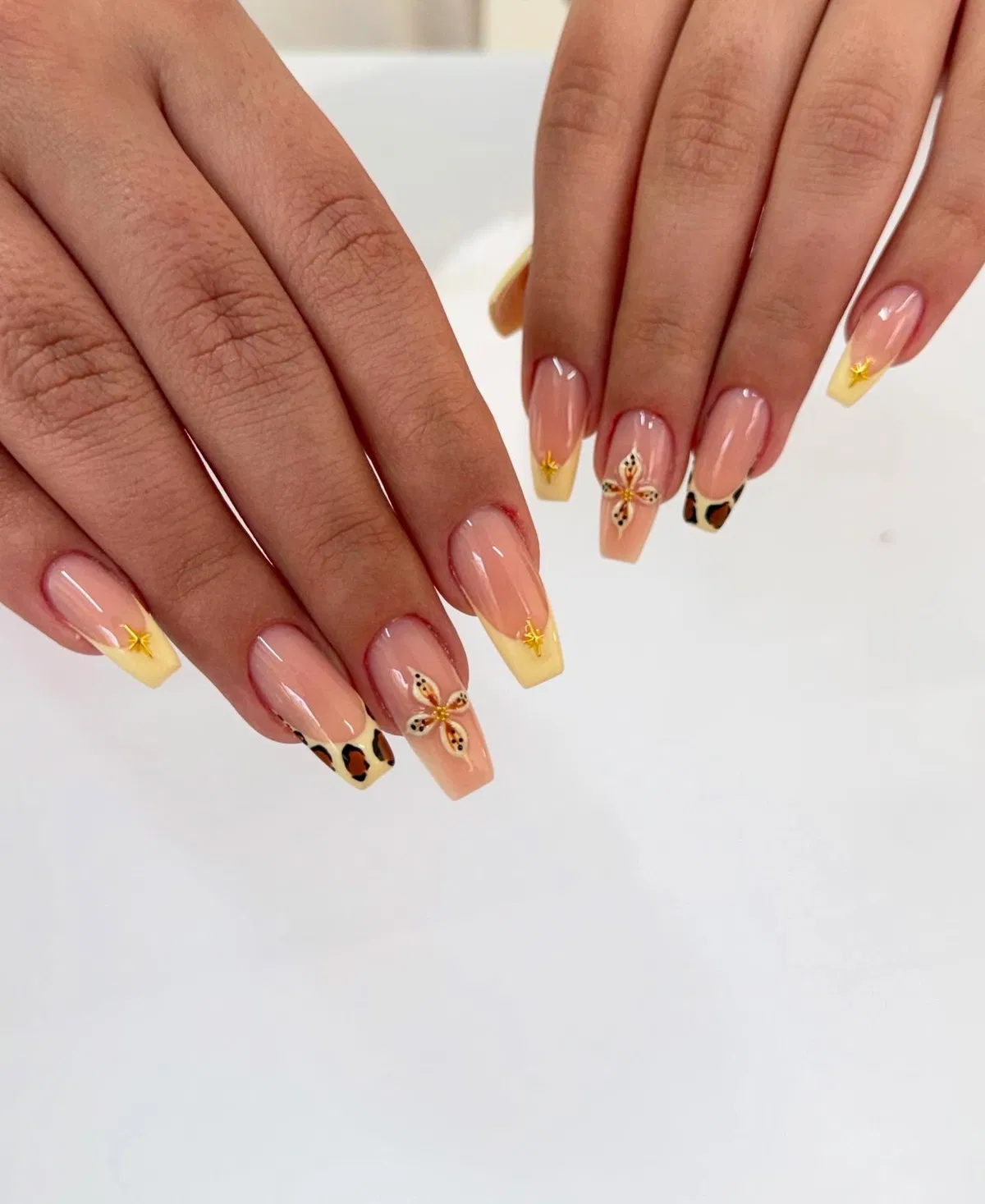 Yellow French tips with star charms, butterfly accent, and animal-print detail