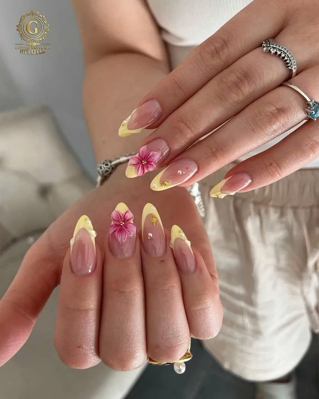 Pale yellow French tips with pink floral accents and small studs