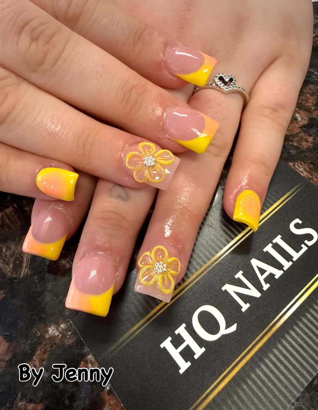 Yellow-to-orange French tips with outlined flower accents and rhinestone centers