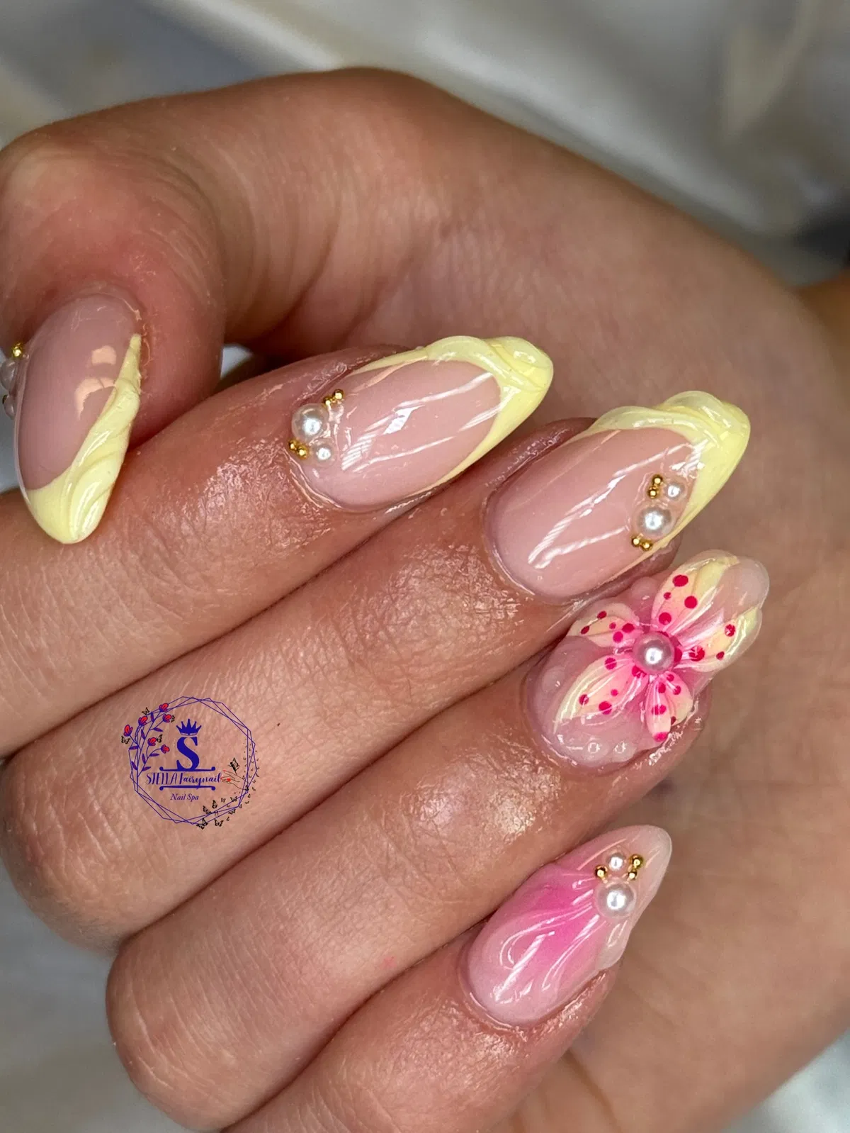 Swirled pale yellow French tips with pearls and a 3D flower accent