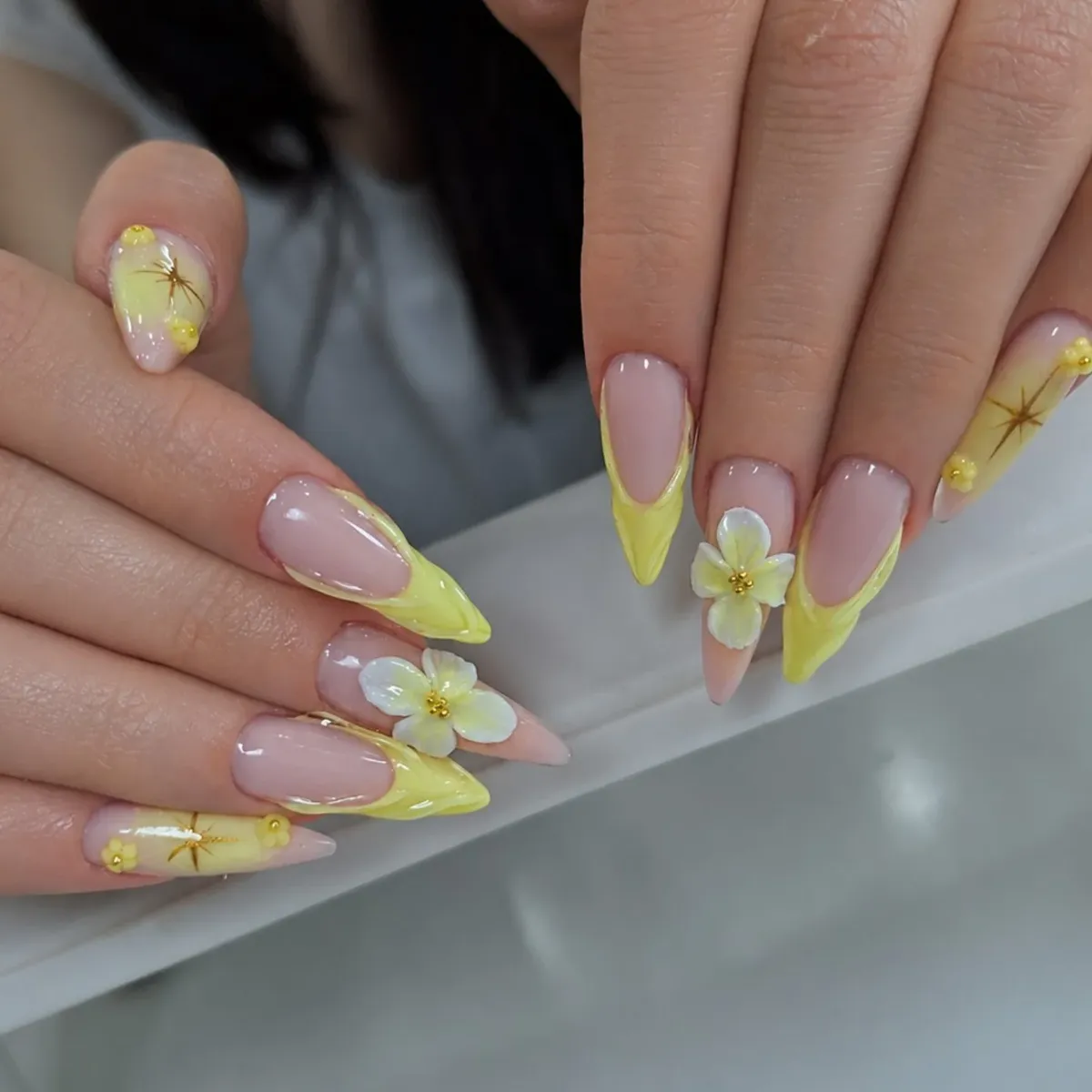 Pale-yellow French tips with gold outlines and 3D white flowers