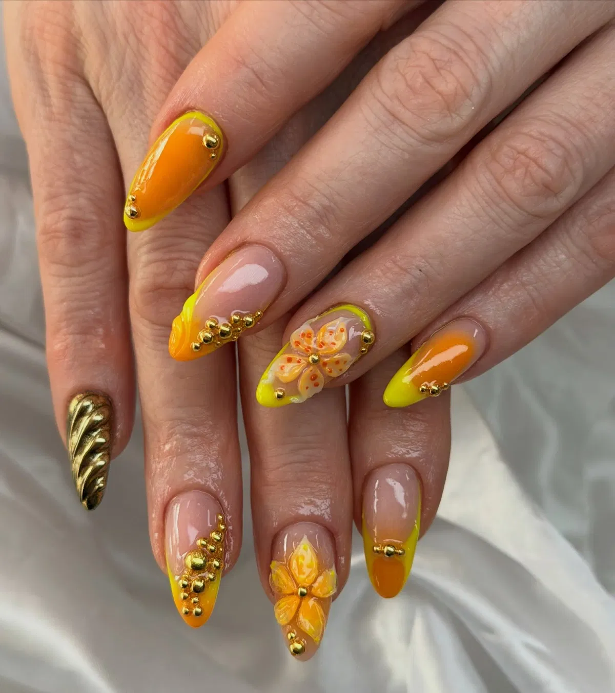 Orange-yellow gradient tips with gold studs and raised florals