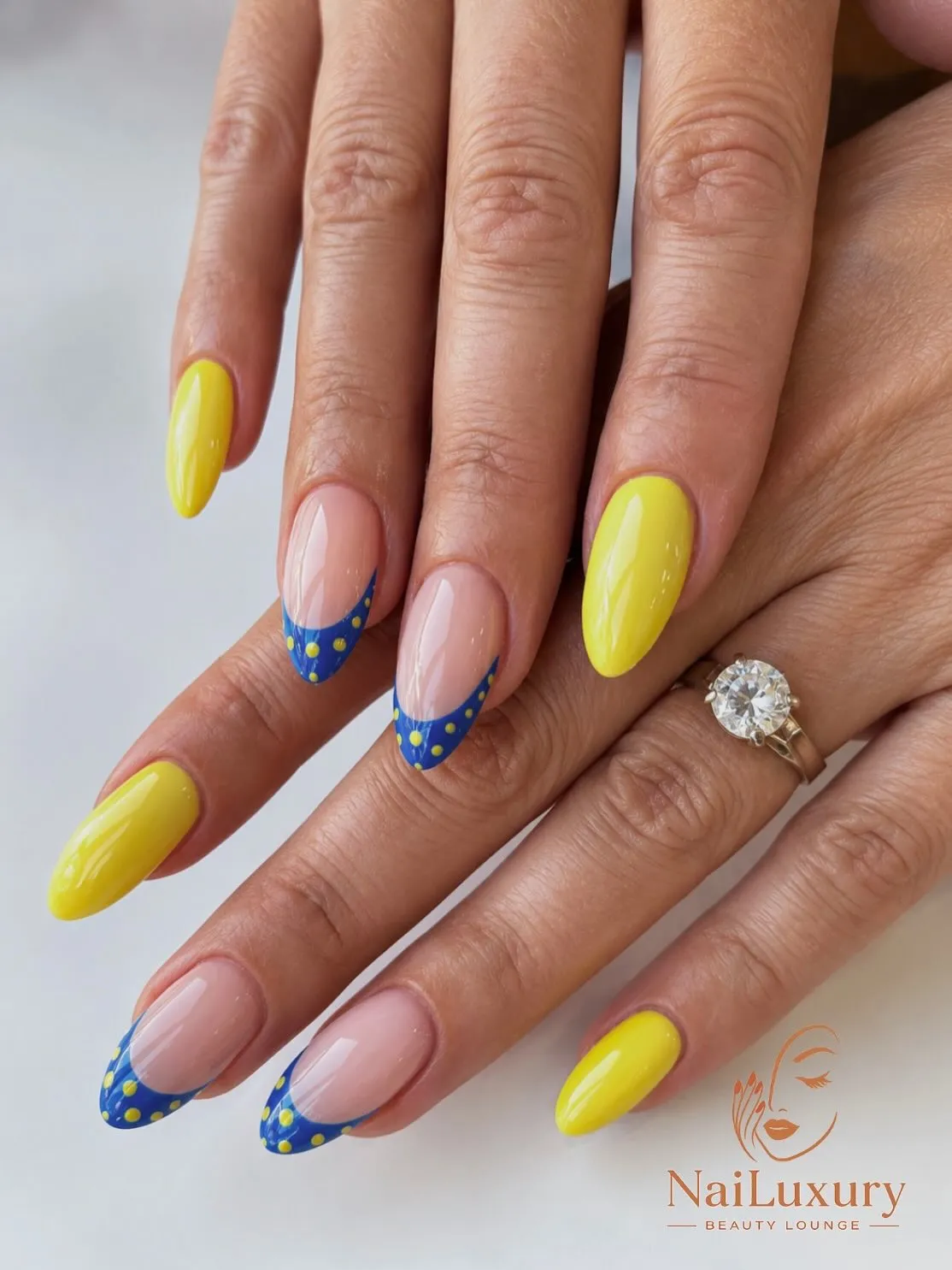 Bright yellow nails with blue dotted French tips