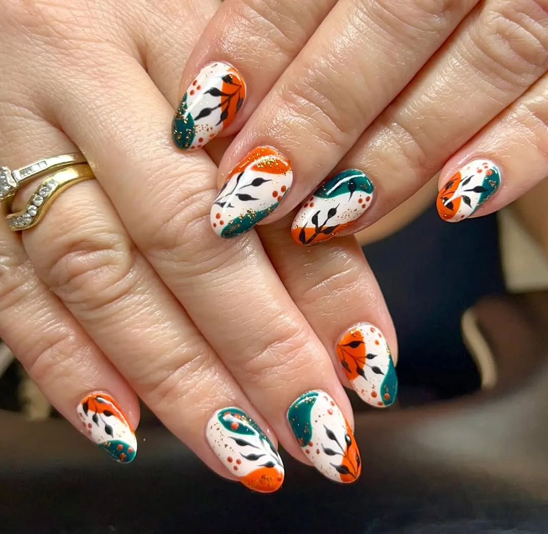 White nails with teal-and-orange swirls and black botanical silhouettes