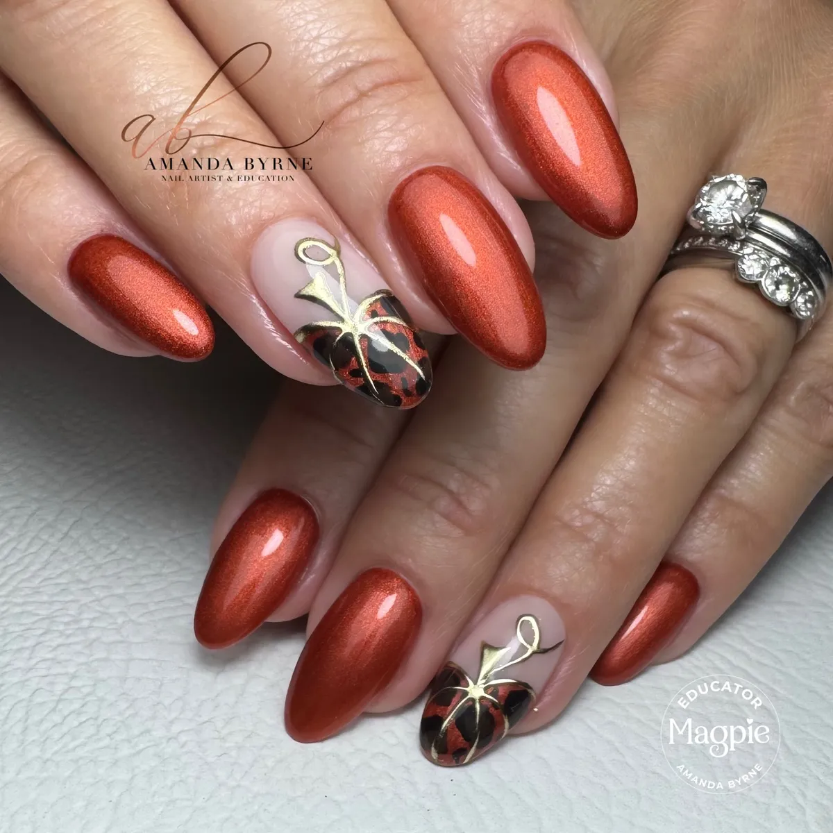 Metallic copper almond nails with gold-outlined pumpkin accents