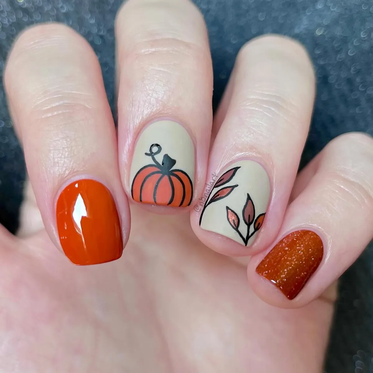Beige line-art pumpkin and leaves with orange accent nails