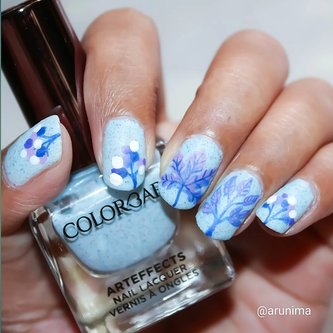 Speckled light blue with leaf-and-berry style nail art
