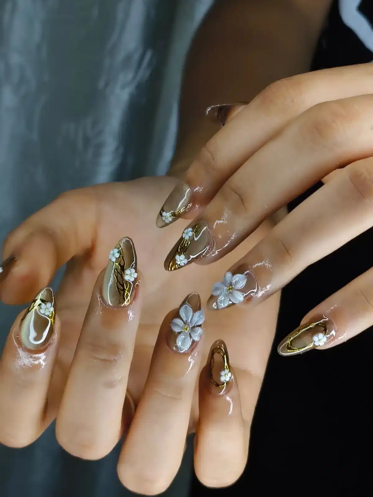 Sheer nude nails with gold outlines and 3D white flowers