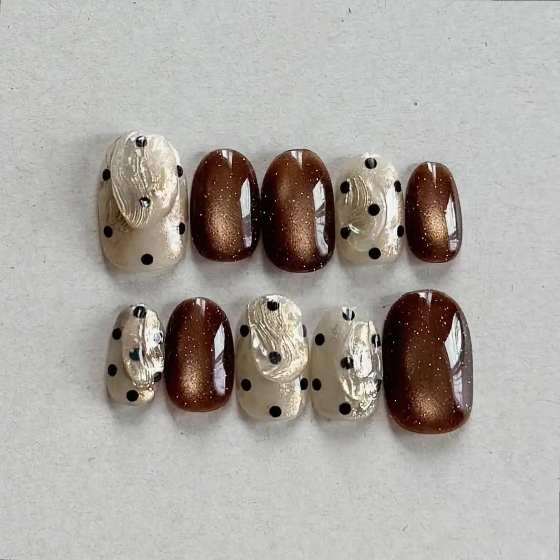 Brown reflective nails with dotted textured cream accents