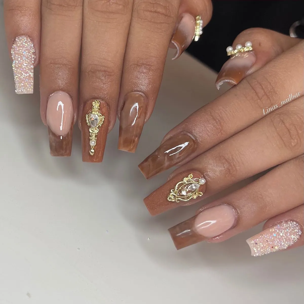 Brown marble coffin nails with ornate gold-toned embellishments