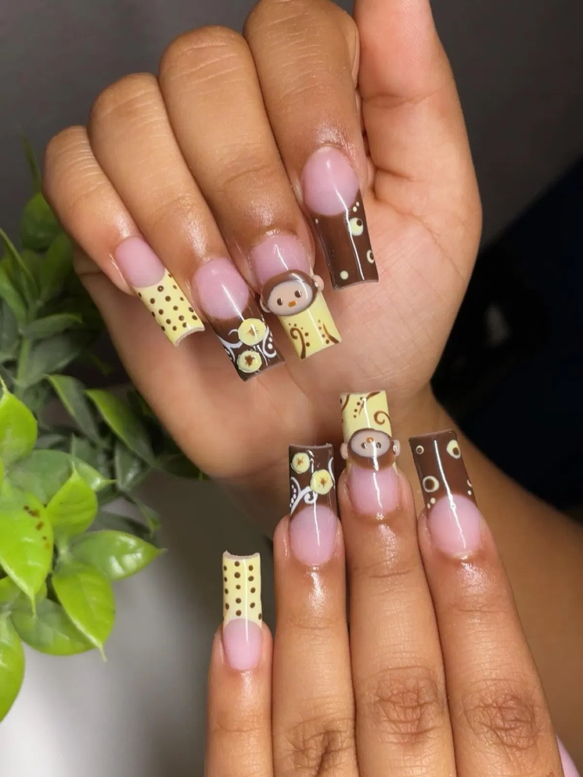 Brown and pale-yellow square nails with dot patterns and monkey faces