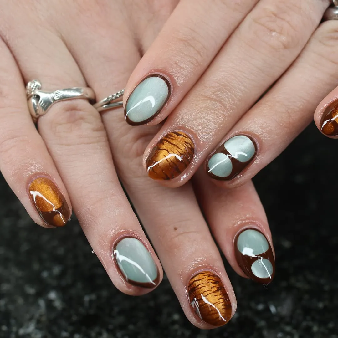 Gray-green nails with brown outlines and striped amber accents