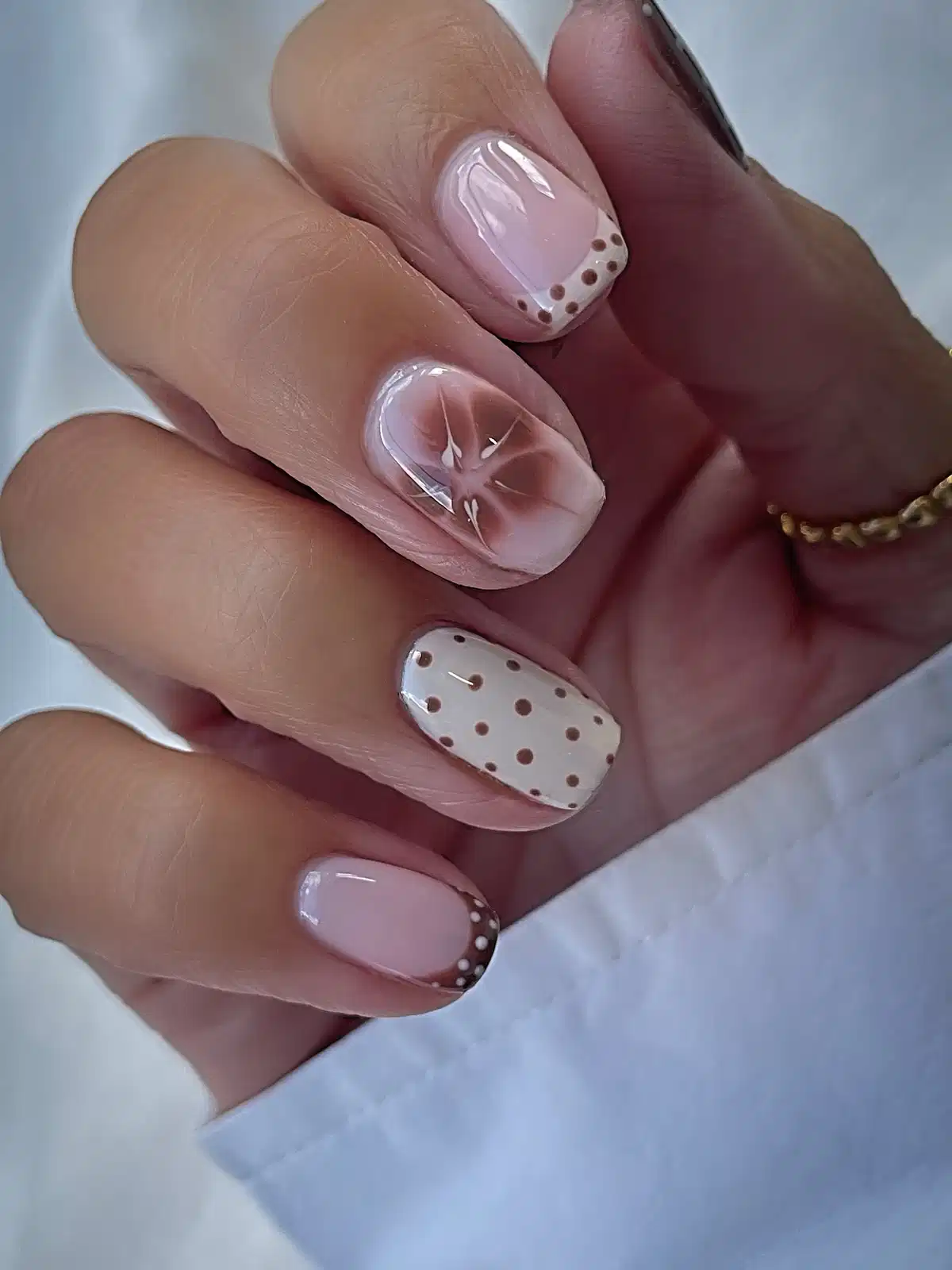 Short pink set with dotted French tips and soft brown floral accent