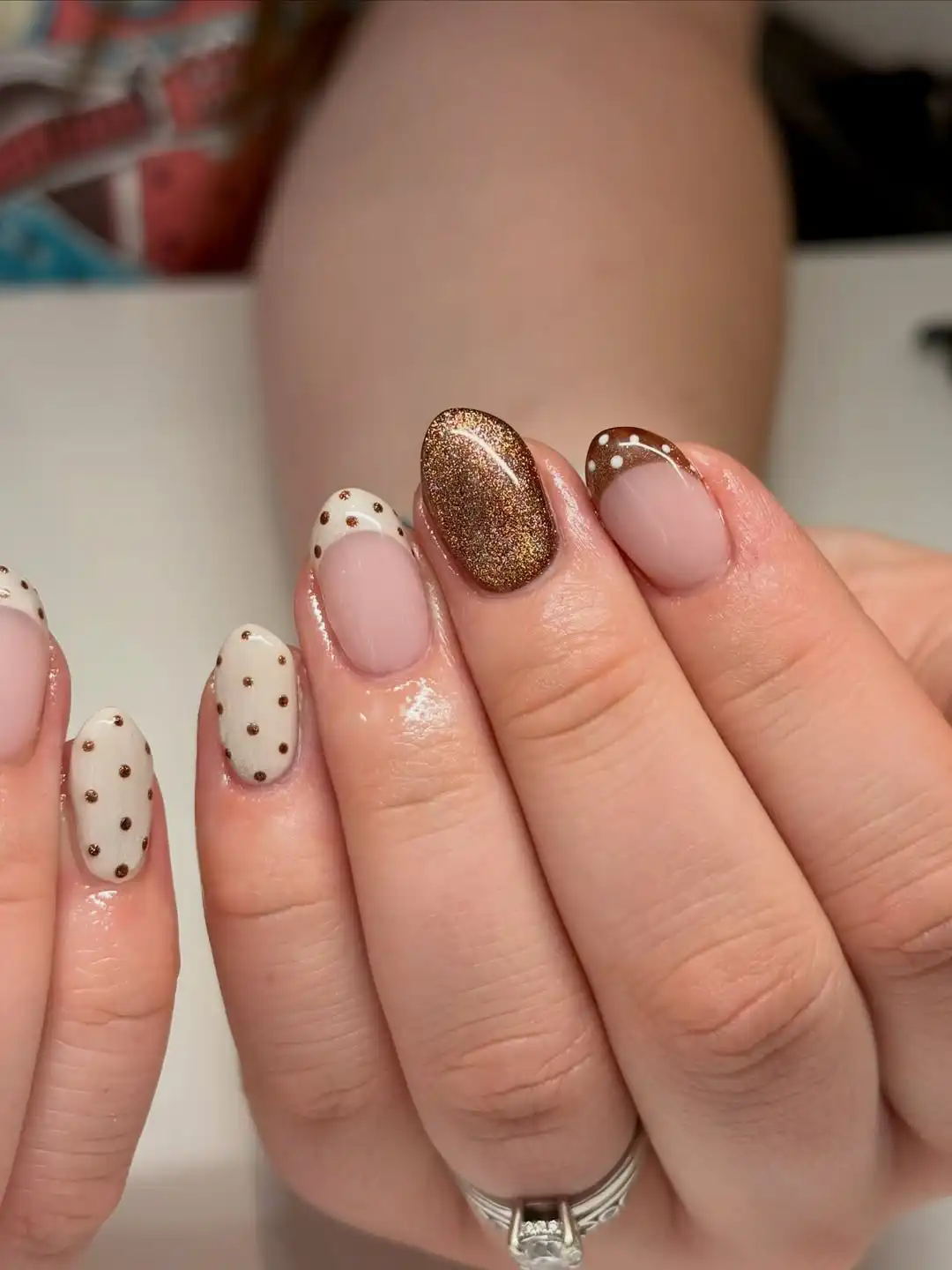 Brown French tips with dotted details and a glitter accent nail