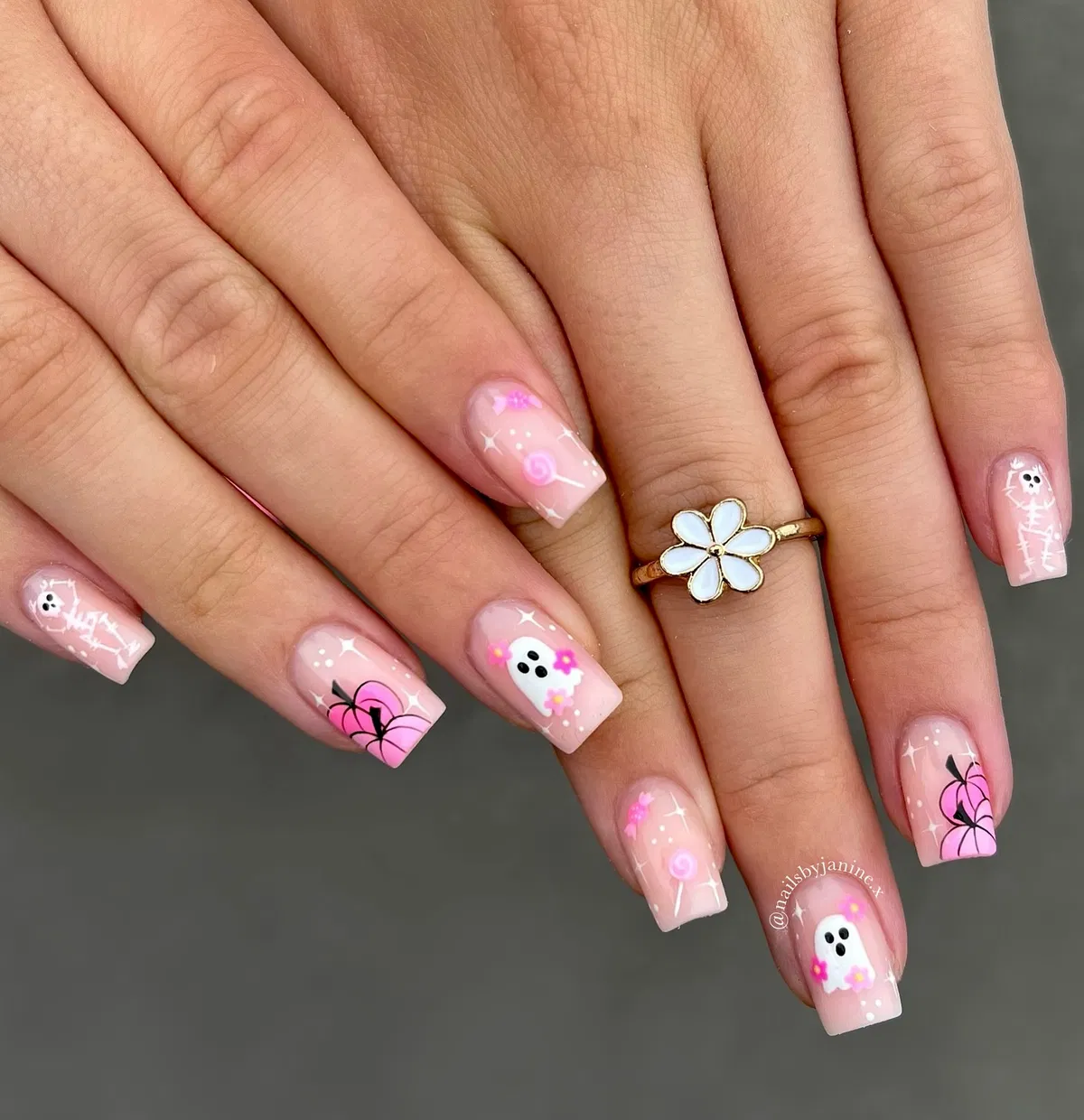 Soft pink sparkly nails with ghosts, webs, skeletons, and a lollipop detail