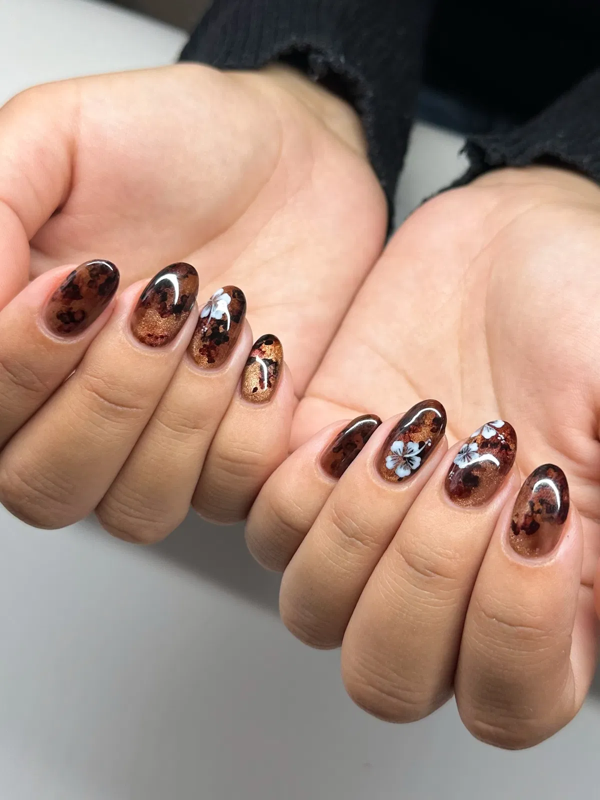 Brown mottled nails with white floral accents