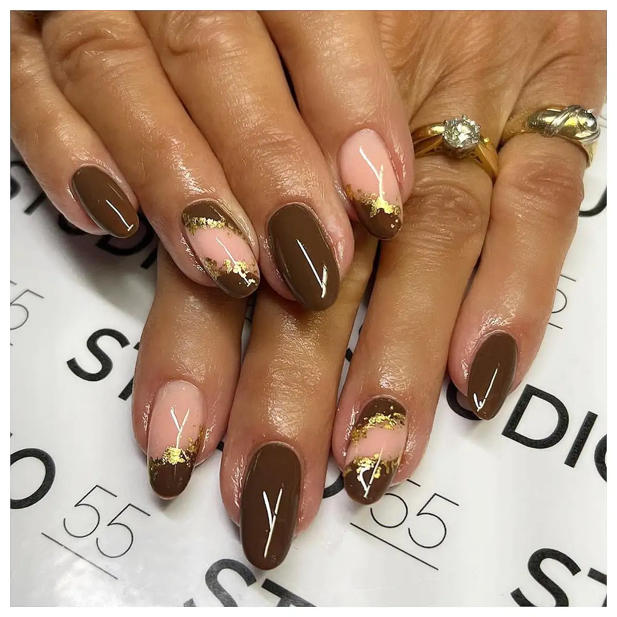 Glossy brown and nude-pink tips with gold foil accents