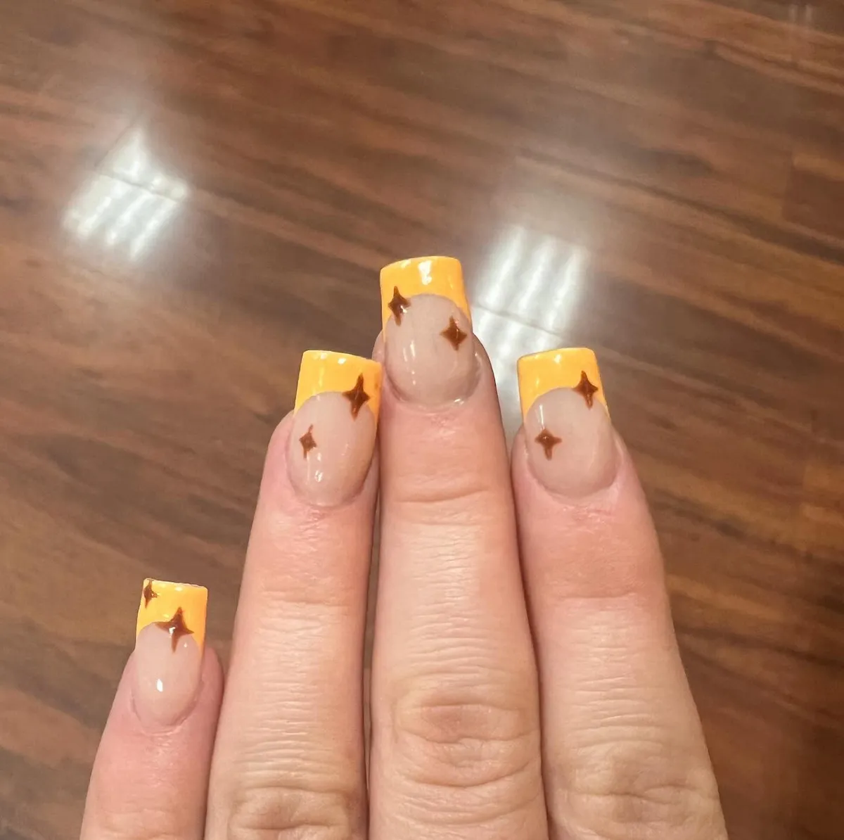 Yellow French tips with small brown stars