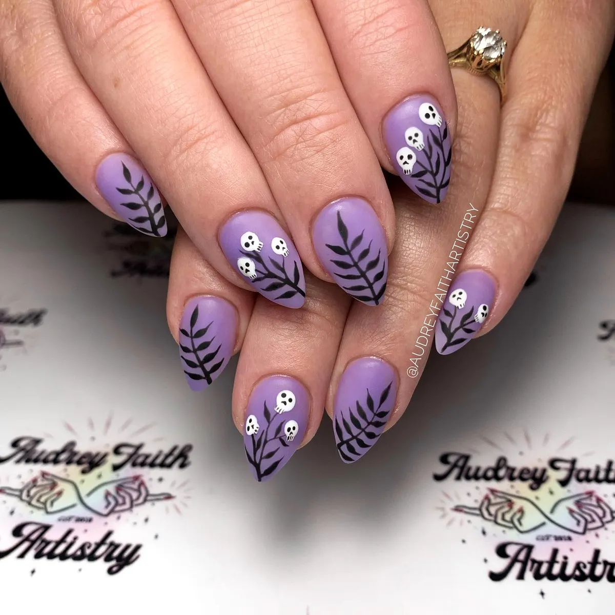 Lavender nails with black branches and tiny white skulls