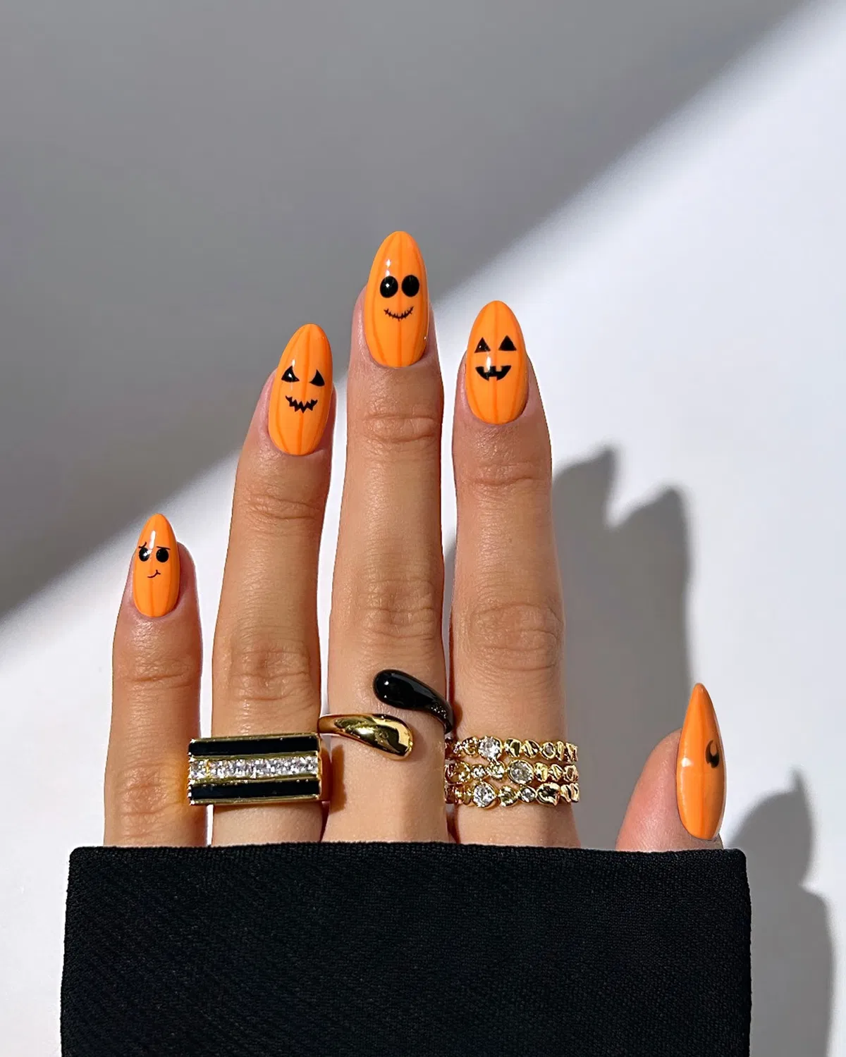 Bright orange pumpkin-face nails with black facial features