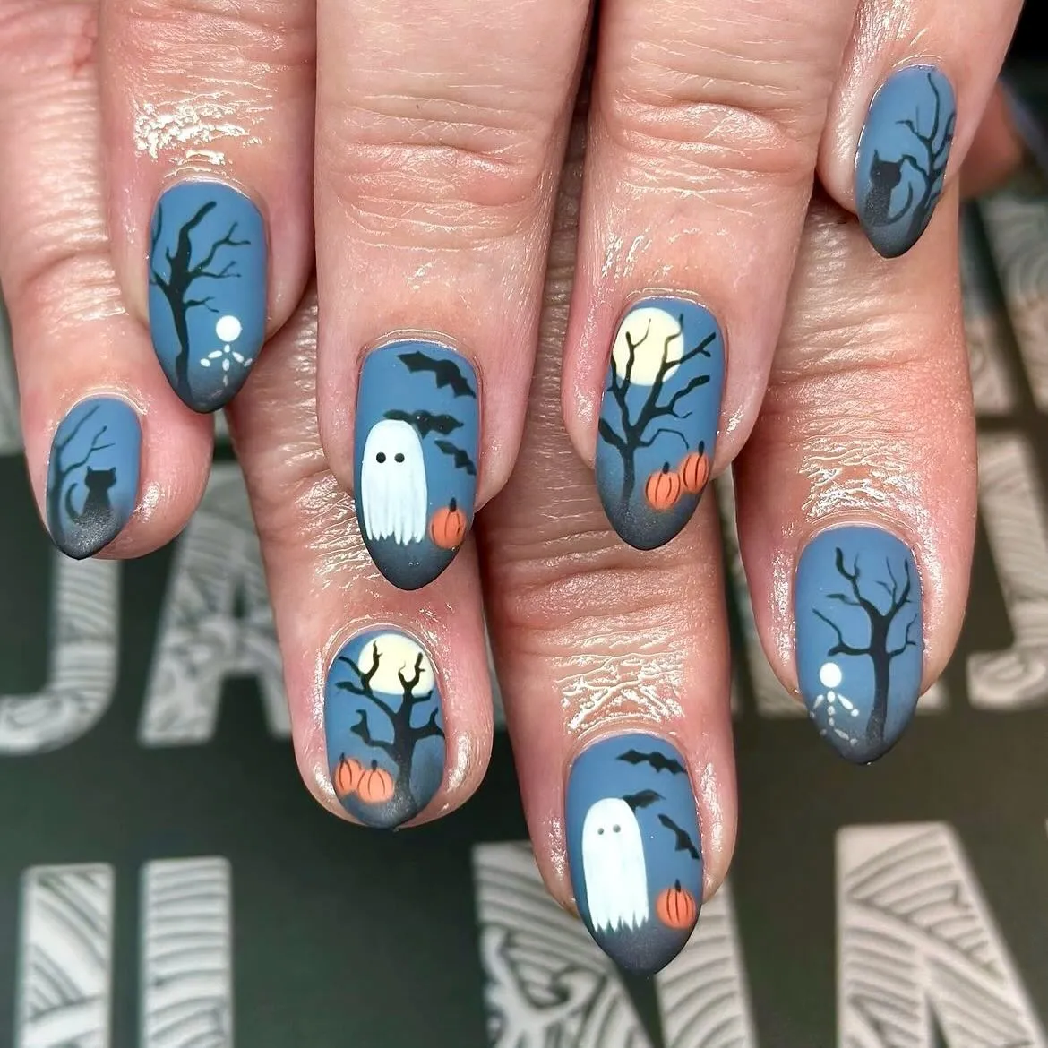 Moody blue-gray silhouettes with trees, moon, ghosts, bats, and pumpkins
