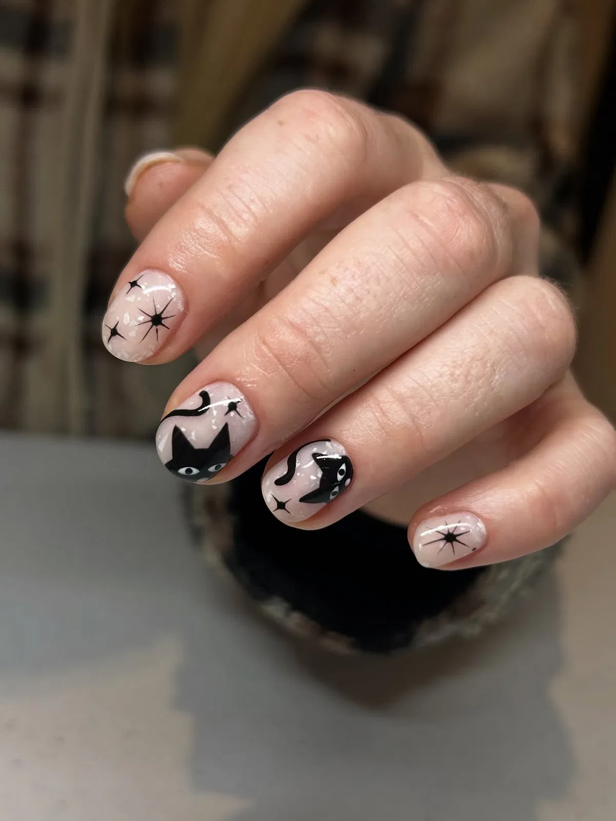 Nude glossy nails with black cats and starburst accents